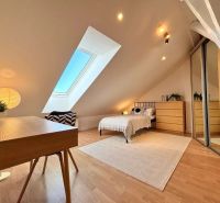 Attic room with a table, bed, and mirrored wardrobe in a 4-room apartment.