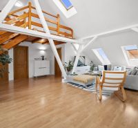 Bright attic living room with a gallery and wooden decor flooring.
