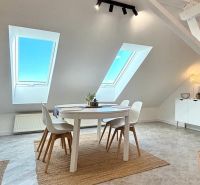 Dining nook with skylights and a round table in a 4-room apartment.