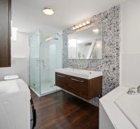A bathroom in a 4-room apartment with a mosaic wall and a floor with a wooden decor.