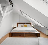 Attic bedroom with a sloped ceiling, wooden decor flooring, double bed.