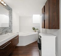 A bathroom in a 4-room apartment with a double sink, a bathtub, and a wooden decor floor.