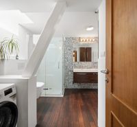 Bathroom with a shower, washing machine, and a floor with a wooden decor in a 4-room apartment.