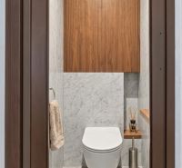 A bathroom in a one-room apartment with wooden paneling and marble tiles.