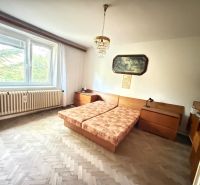 Bedroom in a family house with parquet flooring and a large window.