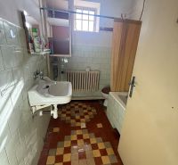 A bathroom in a family house with a colorful floor, a sink, and a shower curtain.