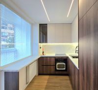 The kitchen in a 3-room apartment with a wooden decor floor and elegant cabinets.