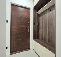 Entrance hall in a 3-room apartment with doors and furniture featuring a wood decor.