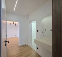 A hallway in a 3-room apartment with a wooden decor floor and a circular mirror.