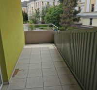 A balcony of a family house in Poprad with a view of the green yard and buildings.
