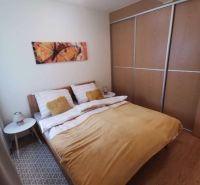 Bedroom in a family house with a bed, painting, and wooden decor flooring.