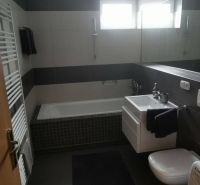A bathroom in a family house with a bathtub, sink, toilet, and striped tiles.