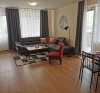 Living room in a family house with wood-patterned flooring, a gray sofa, and a dining table.