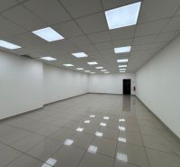 Spacious interior of commercial premises with tiled flooring and a white ceiling full of lighting.
