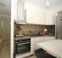 A kitchen in a 2-room apartment with white cabinets and stainless steel appliances.