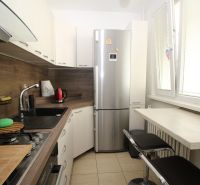 A kitchen in a 2-room apartment with a corner unit, a refrigerator, and a bar counter.
