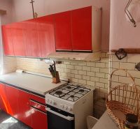 A kitchen in a family house with older red furniture and a gas stove.