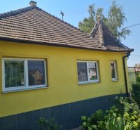 A family house in Komjatice with a flower garden and a yellow facade.