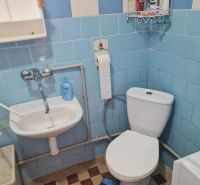 A bathroom in a family house with blue tiles, a sink, and a toilet.