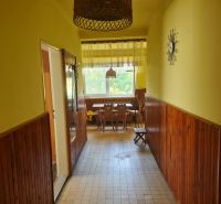 A hallway in a family house with wooden paneling and a view of the dining area.