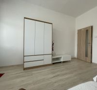 White wardrobe and furniture in a room with wood-patterned flooring in a 3-room apartment.