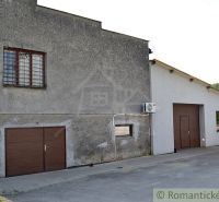 The exterior of a family house in Varadka with a garage door and a window with an anti-burglary screen.