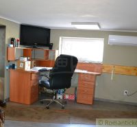 A workspace in a family house with an office desk, shelves, and a television on the wall.
