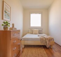 Cozy bedroom in a 3-room apartment with a bed, dresser, and wooden decor flooring.