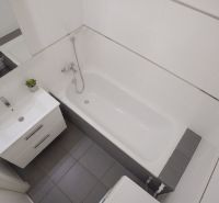 A bathroom with a bathtub, washing machine, sink, and white tiles in a 3-room apartment.
