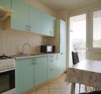 A kitchen in a 3-room apartment with green cabinets, a dining table, and a gas stove.