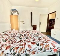 A bedroom in a family house with a bed, stove, and wardrobe, decorated with floral beddings.