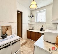 A kitchen in a family house with white tiles and appliances on the counter.
