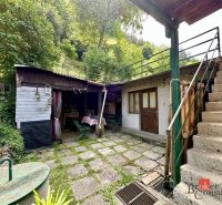 The courtyard of a family house in Žiar nad Hronom with a staircase and a wooden annex surrounded by greenery.