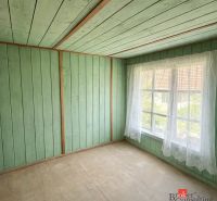 A room in a family house with wooden wall paneling and a large window.