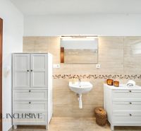 Bathroom in a family house with a sink, mirror, and white furniture.