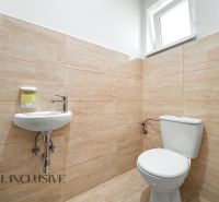 A bathroom in a family house with light tiles and a small sink.