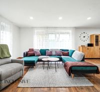 Living room with a sofa, armchair, and wood-patterned flooring in a family house.