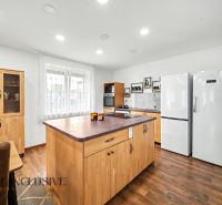 A kitchen in a family house with wooden decor, white appliances, and an island.