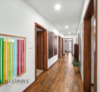A hallway in a family house with a wooden decor floor and a colorful wall piece.
