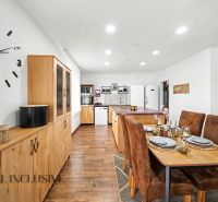 A dining room with wooden decor, a wall clock, and an elegantly set table in a family house.