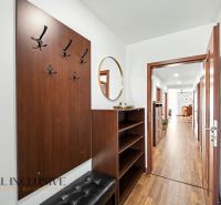 A hallway in a family house with a mirror, hooks, and a wooden decor floor.