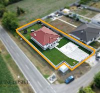 A family house in Vozokany with a red roof, a garden, and a concrete yard along the road.