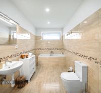 A bathroom in a family house with a bathtub, tiles, and a toilet.