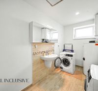 A bathroom in a family house with a washing machine, dryer, and white cabinets.