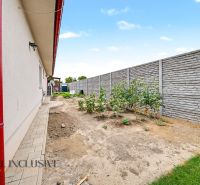 The garden of a family house in Vozokany with a wall, paving, and plants.