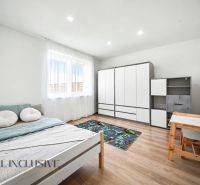 A room with a bed, a desk, a wardrobe, and a wooden-patterned floor.