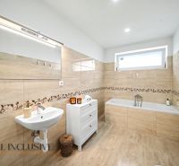 A bathroom in a family house with a bathtub, a mirror, and a white sink.