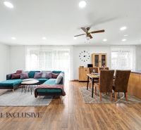 Living room in a family house with wood-patterned flooring, a sofa set, and a dining table.