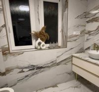 A bathroom in a 2-room apartment with marble tiles and large windows.