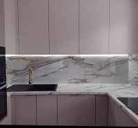 A kitchen in a 2-room apartment with a marble countertop and a black sink.